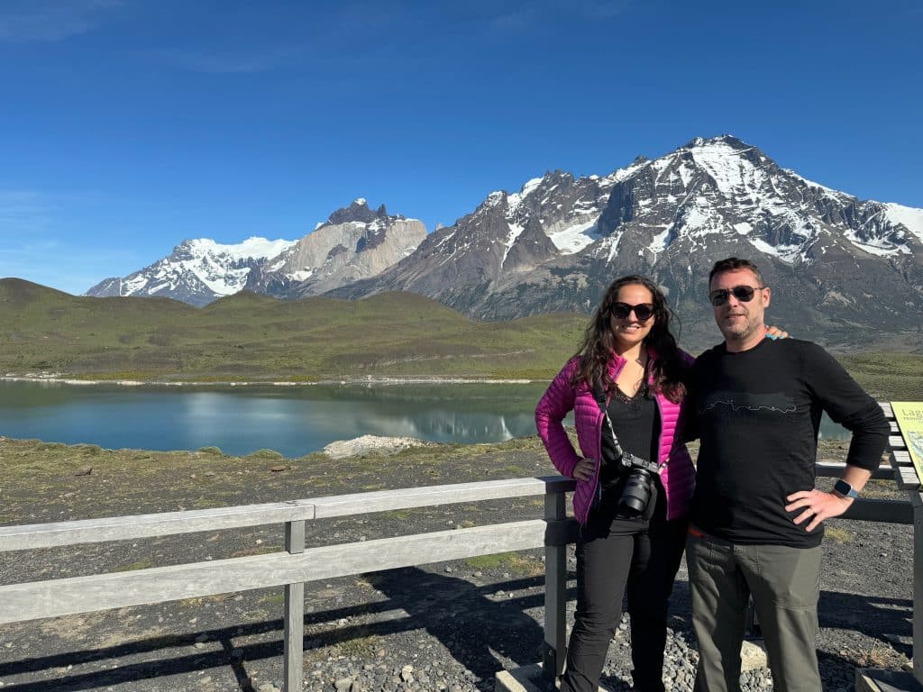 Kate and Charlie standing in front of a lake and snow-covered mountain in Patagonia.
