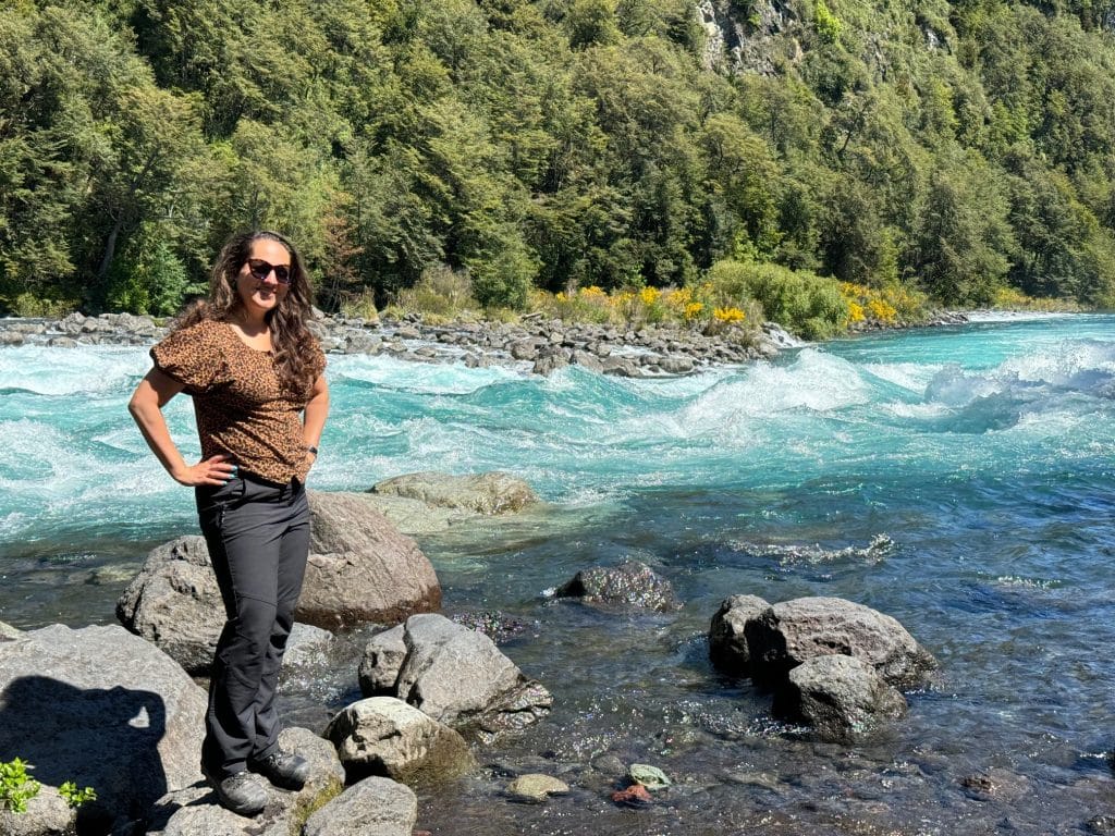 Kate standing on a rock in front of a rushing turquoise river.