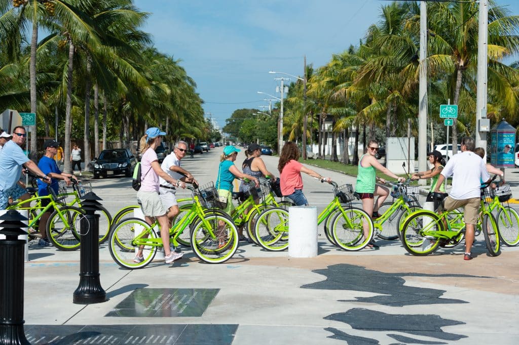 A group of people on a bike tour in Key West, all on lime green bicycles.