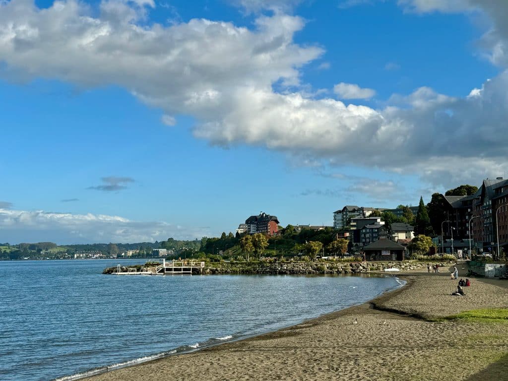 A calm lake beach underneath a blue sky.
