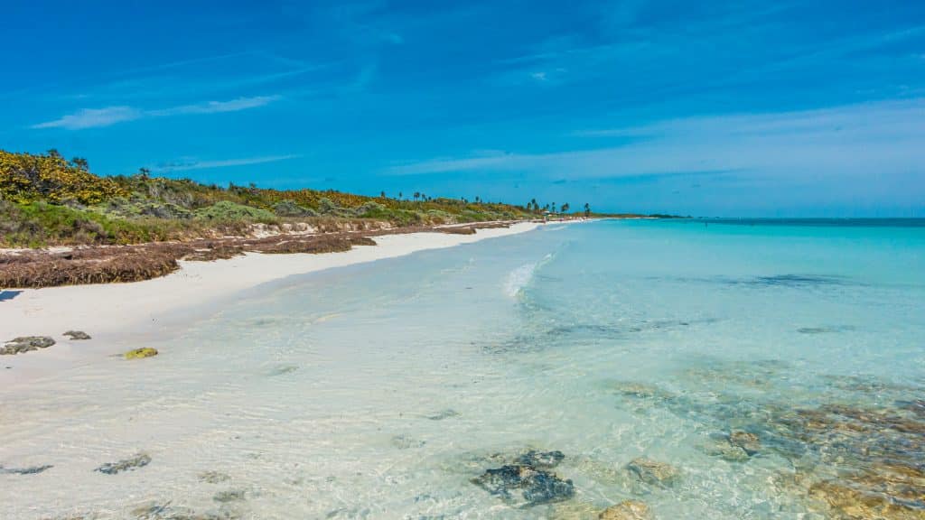 A long, white sand beach with incredibly clear turquoise water.