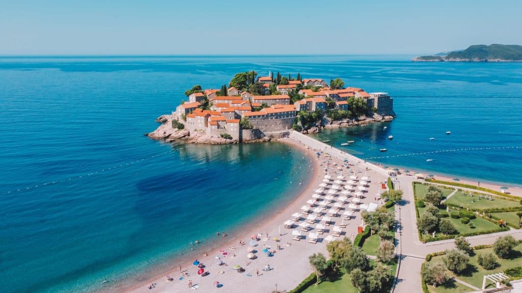 L'île de Sveti Stefan, surmontée de maisons en pierre, et la plage qui y mène.