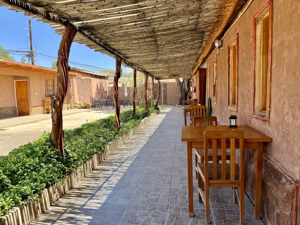 A hotel's courtyard with tables and chairs surrounding an adobe building.