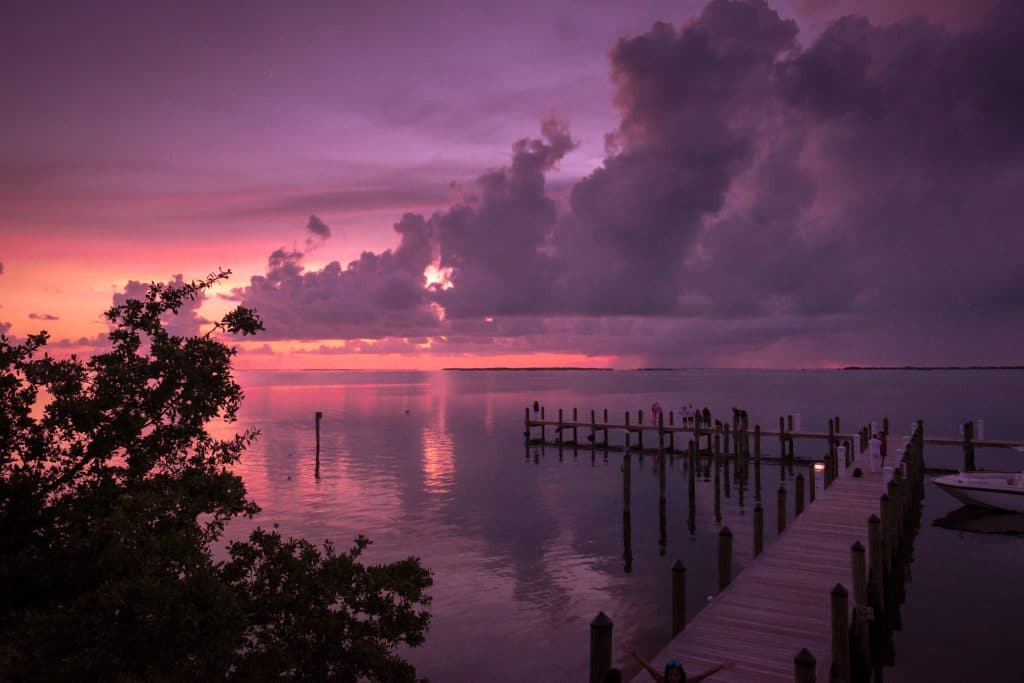 Coucher de soleil rose et violet au bout d'une jetée s'enfonçant dans l'eau à Key Largo, Florida Keys.