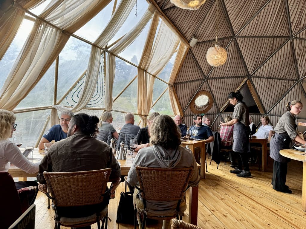 Inside the dining room dome: people sitting at tables, waitstaff serving, and big plastic windows on the side of the dome.