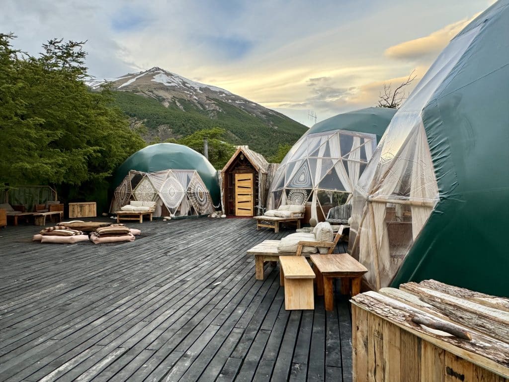 An outdoor deck surrounded by green domes housing the dining room and bar area at Ecocamp Patagonia.