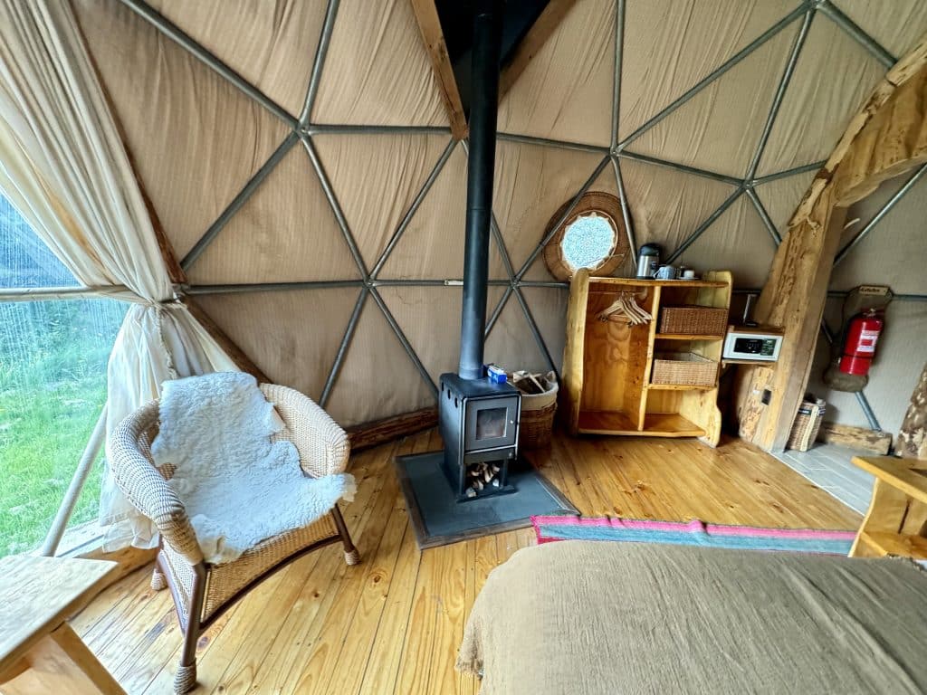 Another view inside the dome hotel room, with a wood stove and small wooden cabinets to be used as a closet.