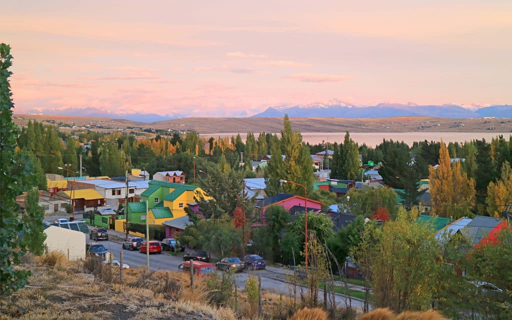 Rows of colorful houses surrounded by trees, perched on the edge of a big lake in Patagonia.