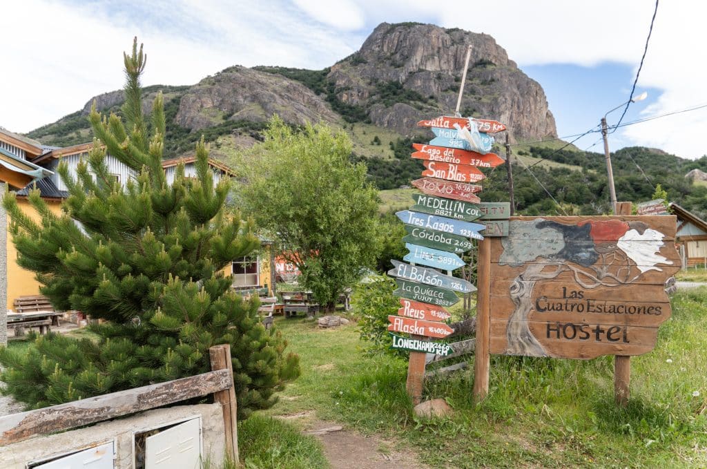 A sign for a hostel with another sign pointing to different cities around the world with arrows pointing in different directions.