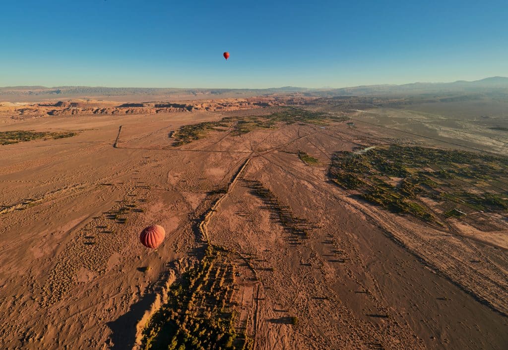 A few hot air balloons sailing over the sandy Atacama Desert, a few oases in the photo.