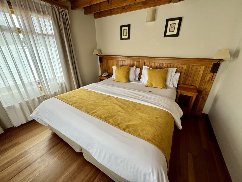 A small hotel room with a big bed covered with a golden bedspread.