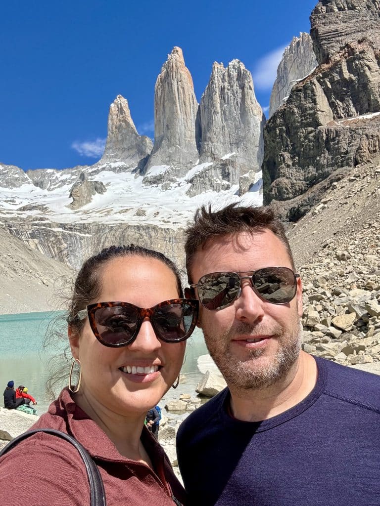 Kate and Charlie taking a smiling selfie in sunglasses in front of the three jagged gray towers.