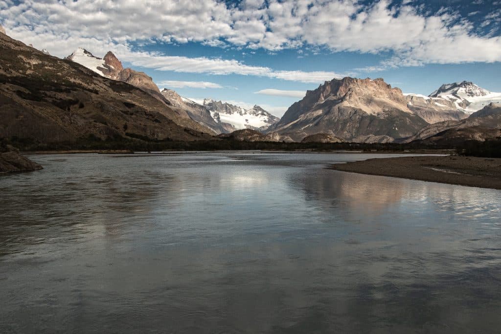 A calm blue lake surrounded by snow-covered mountains.