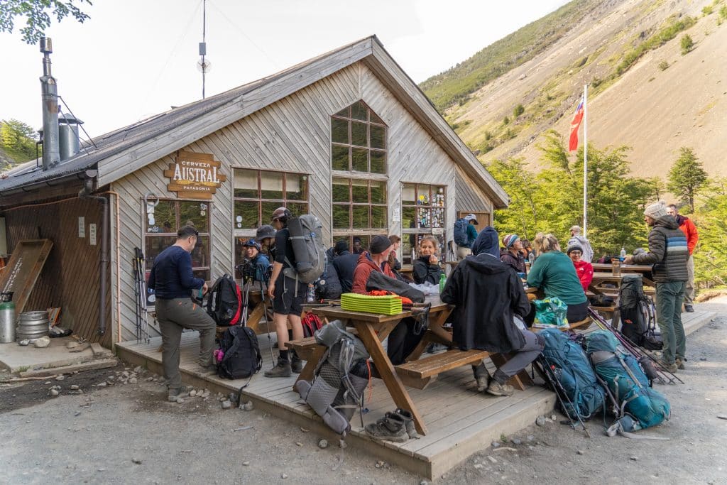 A "refugio" -- a cabin where hikers are taking a break at the picnic tables outside.
