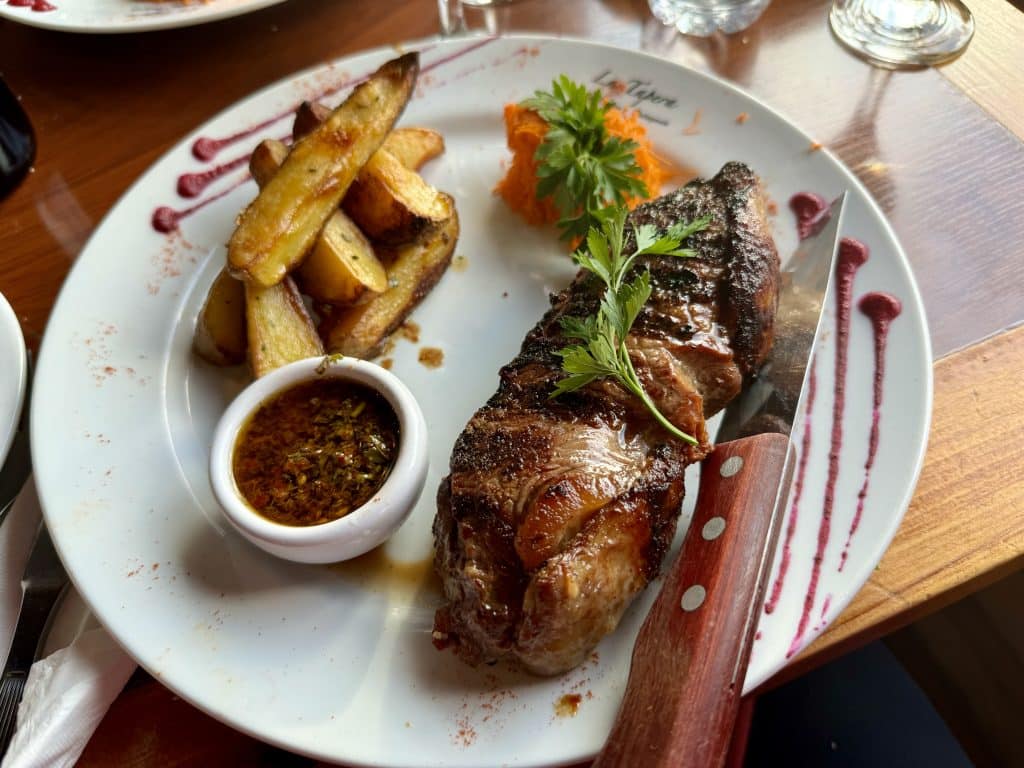 A big, thick steak on a plate, next to some steak fries.