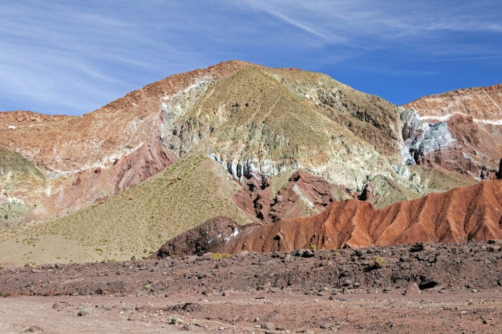 A valley in the desert covered with patches of red, orange, green, and white.