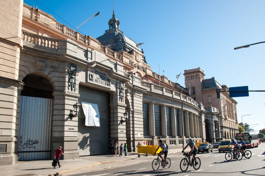 A few cyclists riding past an old building in Buenos Aires.