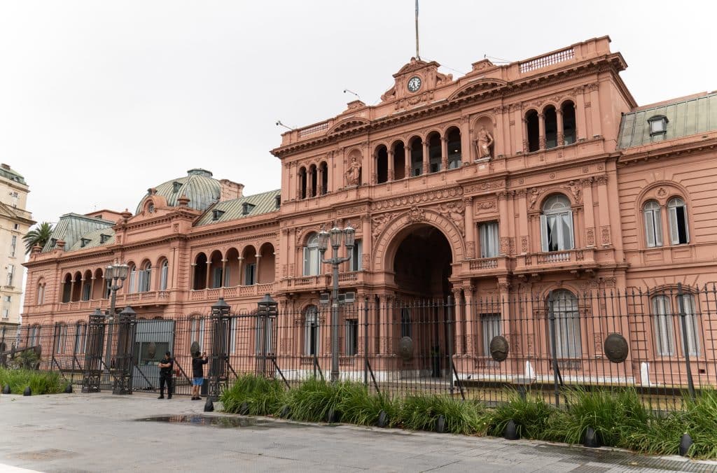 A big pink government building in Buenos Aires with armed guards standing in front.