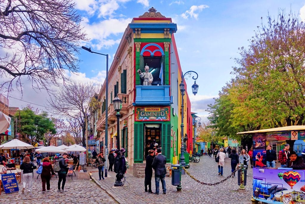 A brightly painted building of many colors in Buenos Aires, people walking around it.