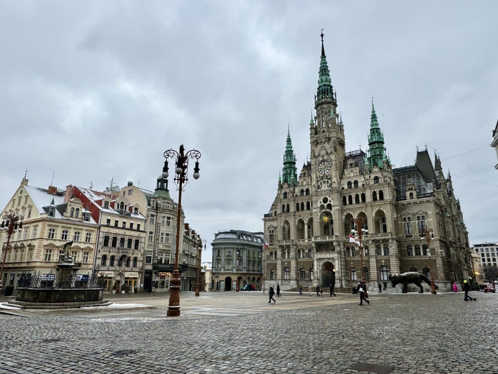 A gray town hall with spiky spires and pointy eaves on a town square in Liberec, Czech Republic.