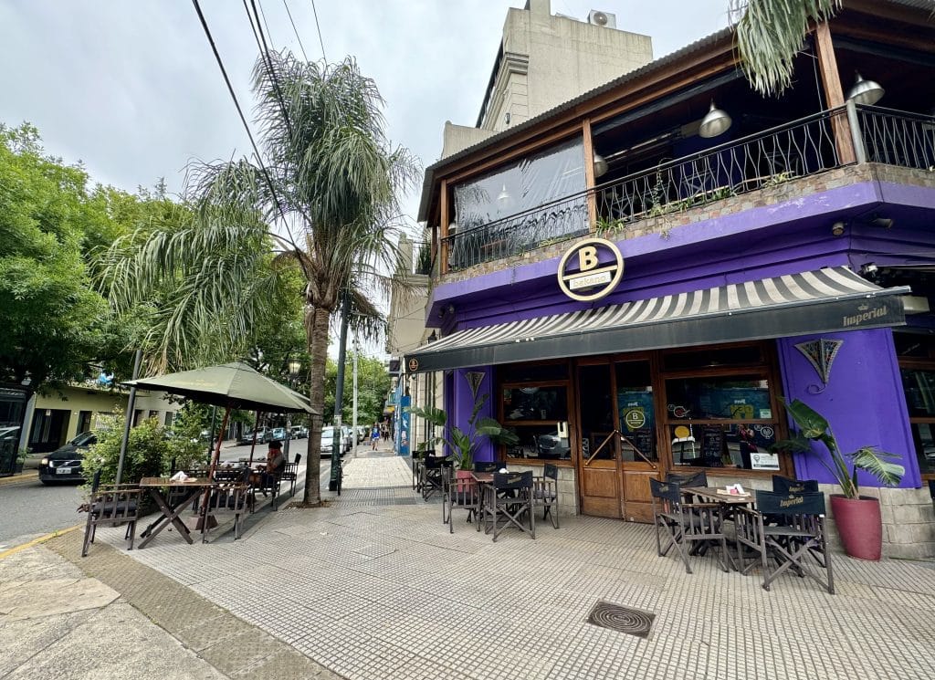A street corner in Palermo, Buenos Aires, with a big purple restaurant, outdoor street seating, and lots of tree-lined streets.