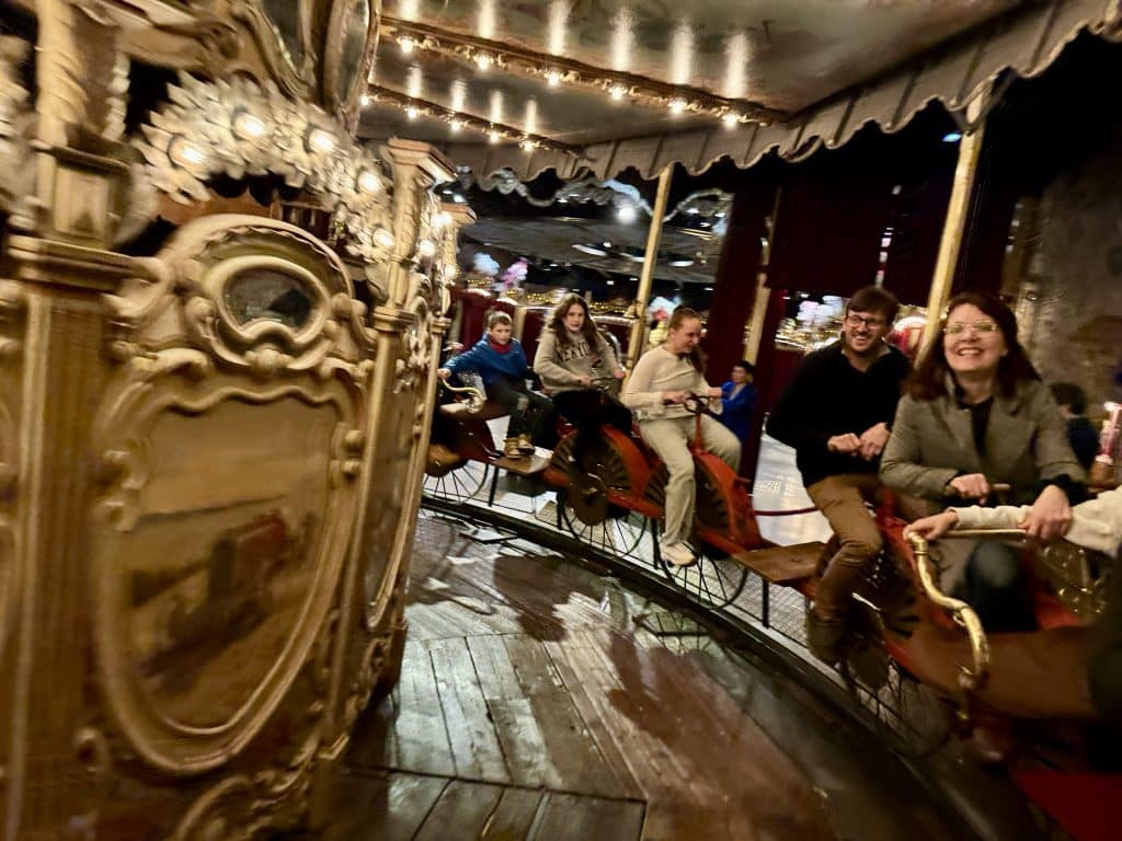 People riding an old-fashioned merry-go-round in Paris with bicycles instead of horses.