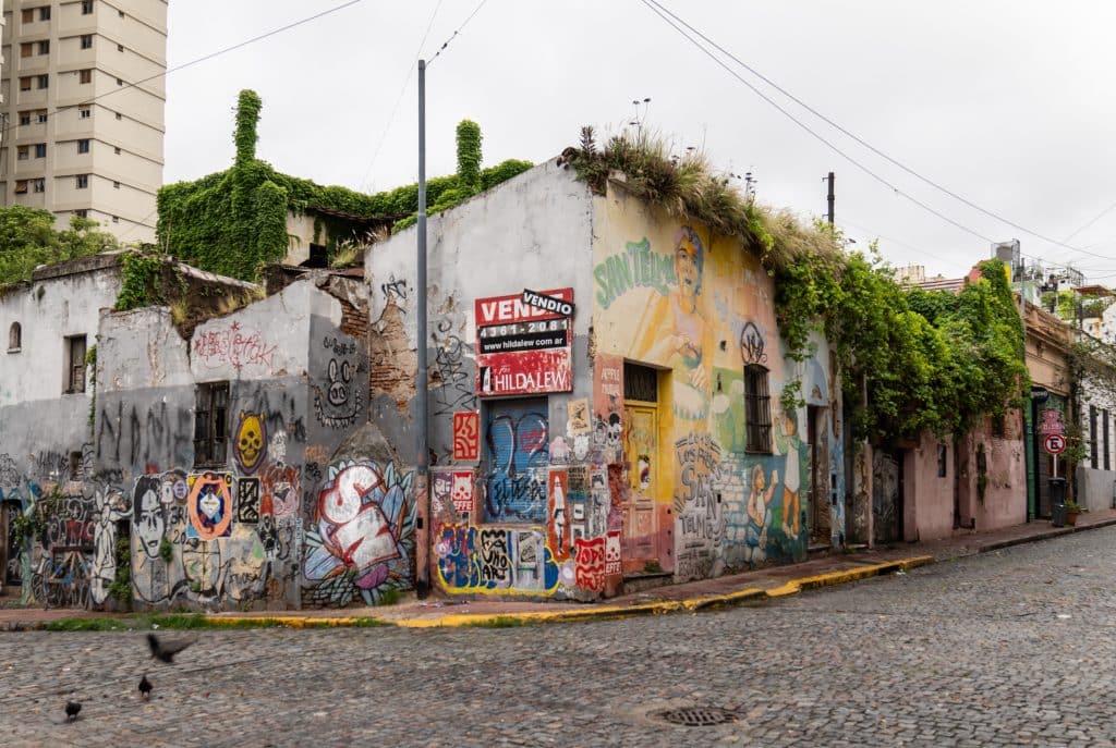 A building on a cobblestone street covered with colorful graffiti.