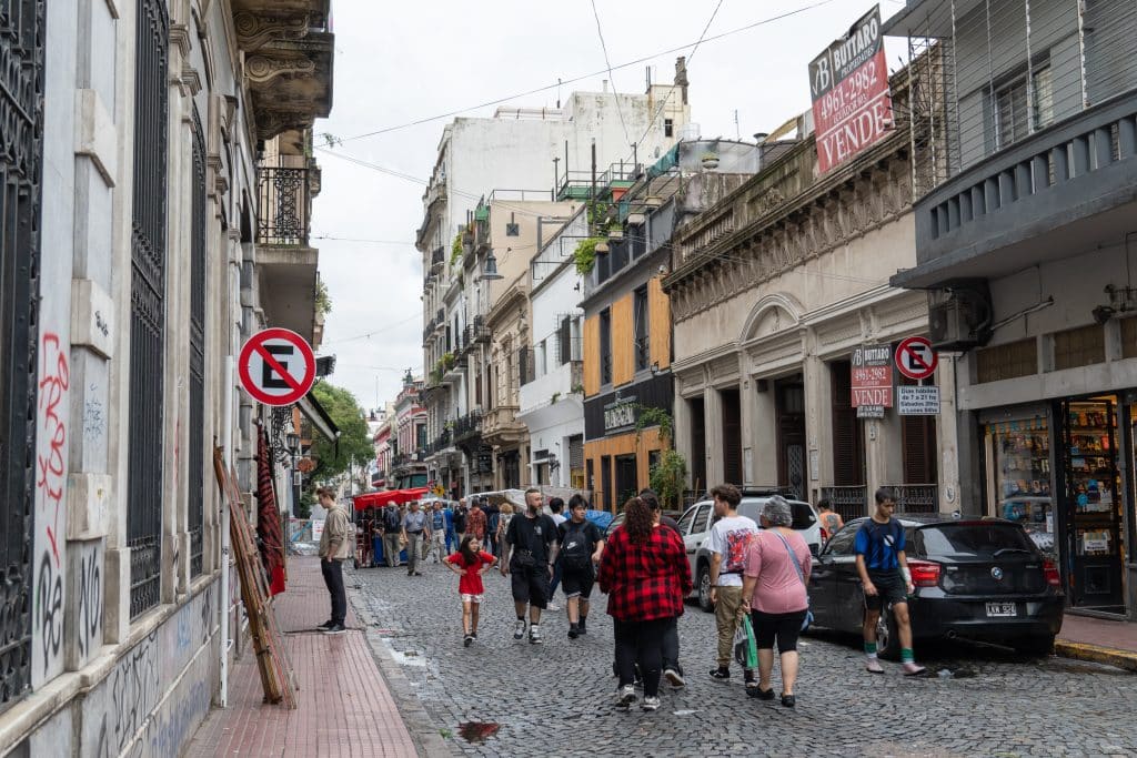A cobblestone street in Buenos Aires on a rainy day, people walking down the street.