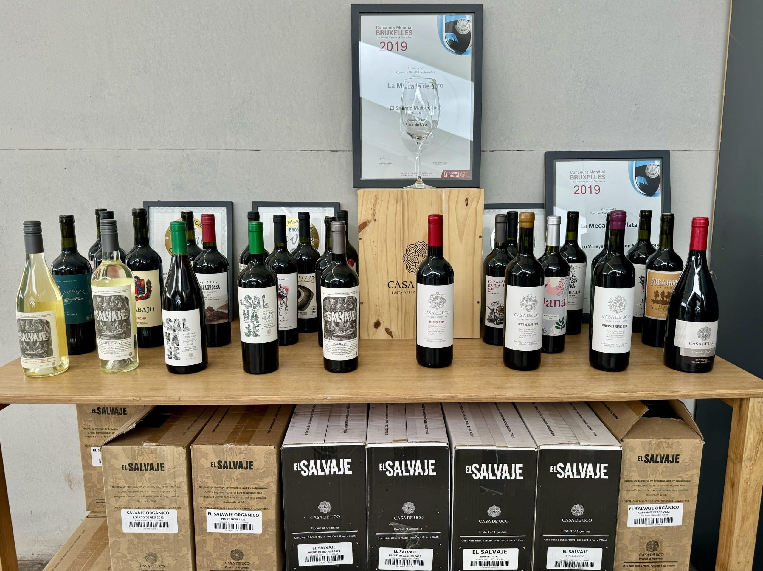 A table with dozens of bottles of Argentine red wine on it.