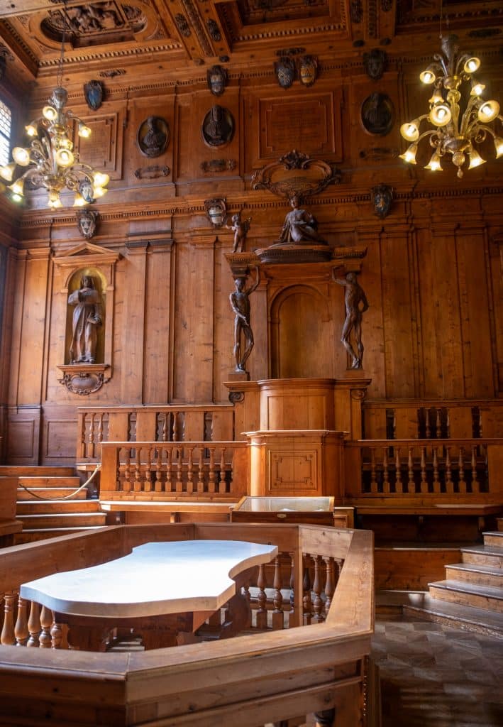 An old-fashioned room with carved wooden walls and statues, with a flat table in the center of the room.