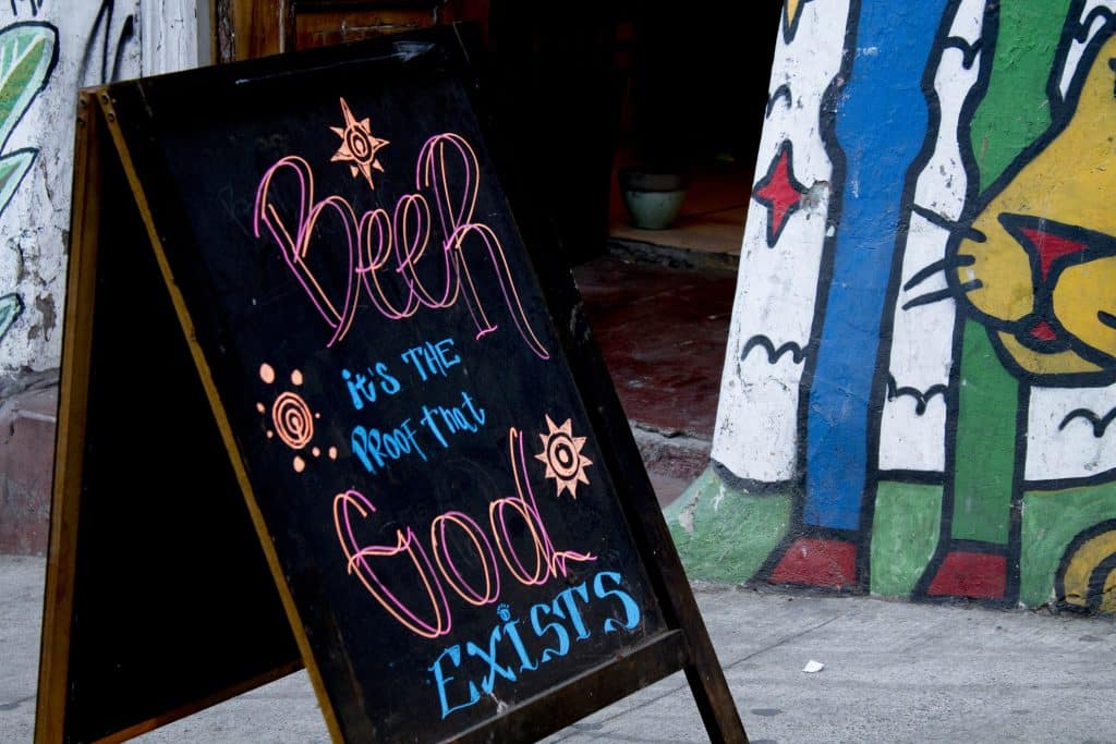 A sign in front of a bar in Valparaiso reading "Beer is proof that God Exists."