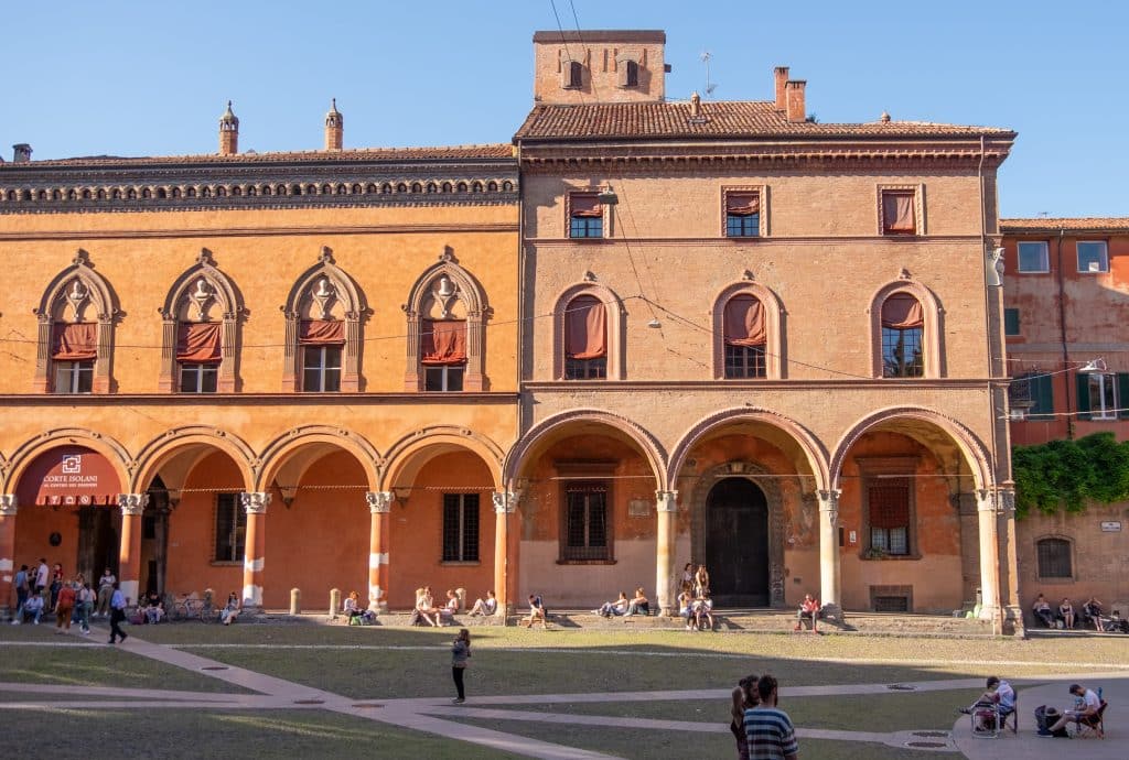 Brightly colored orange and red buildings in Bologna, porticoes underneath.