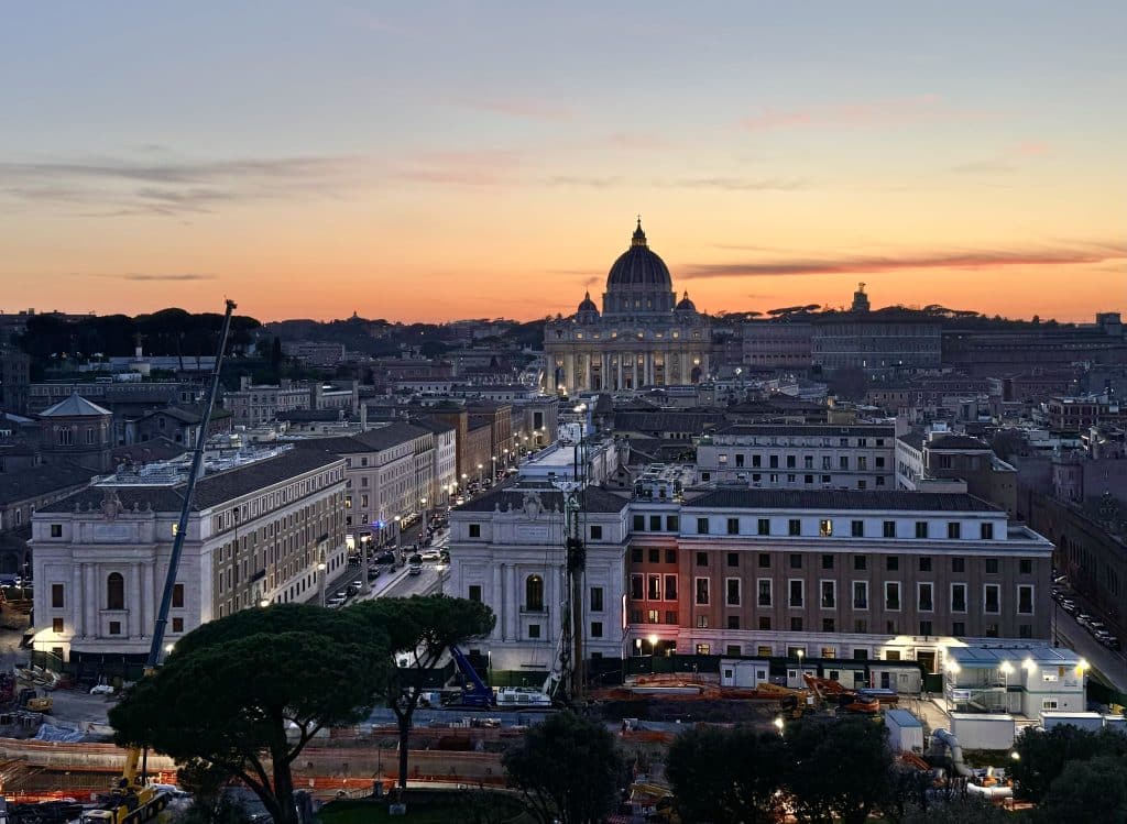 St. Peter's Basilica in the far distance, with an orange sunset lighting up behind it.
