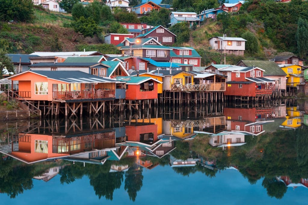 Brightly colored houses on stilts in still water in Chiloe, Chile.