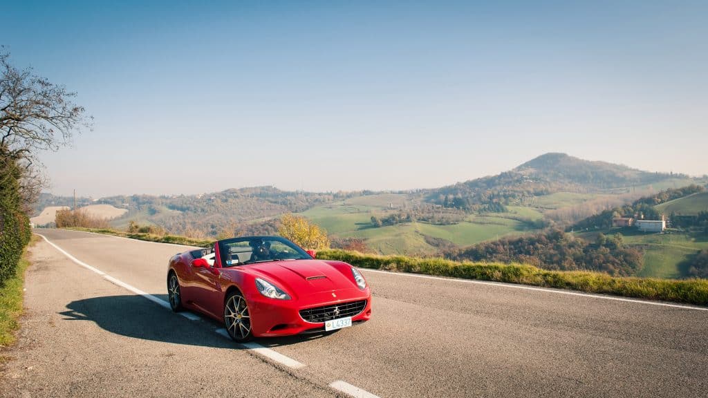 A bright red Ferrari cruising through the Italian countryside.