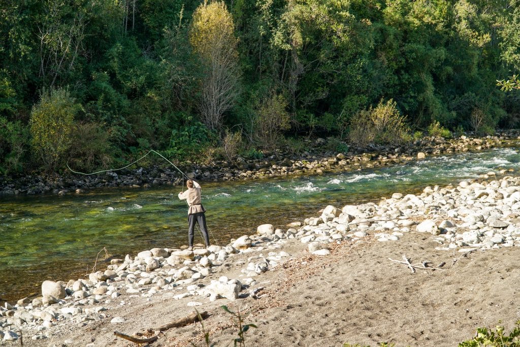 A young man fishing in a clear green river in Chile.