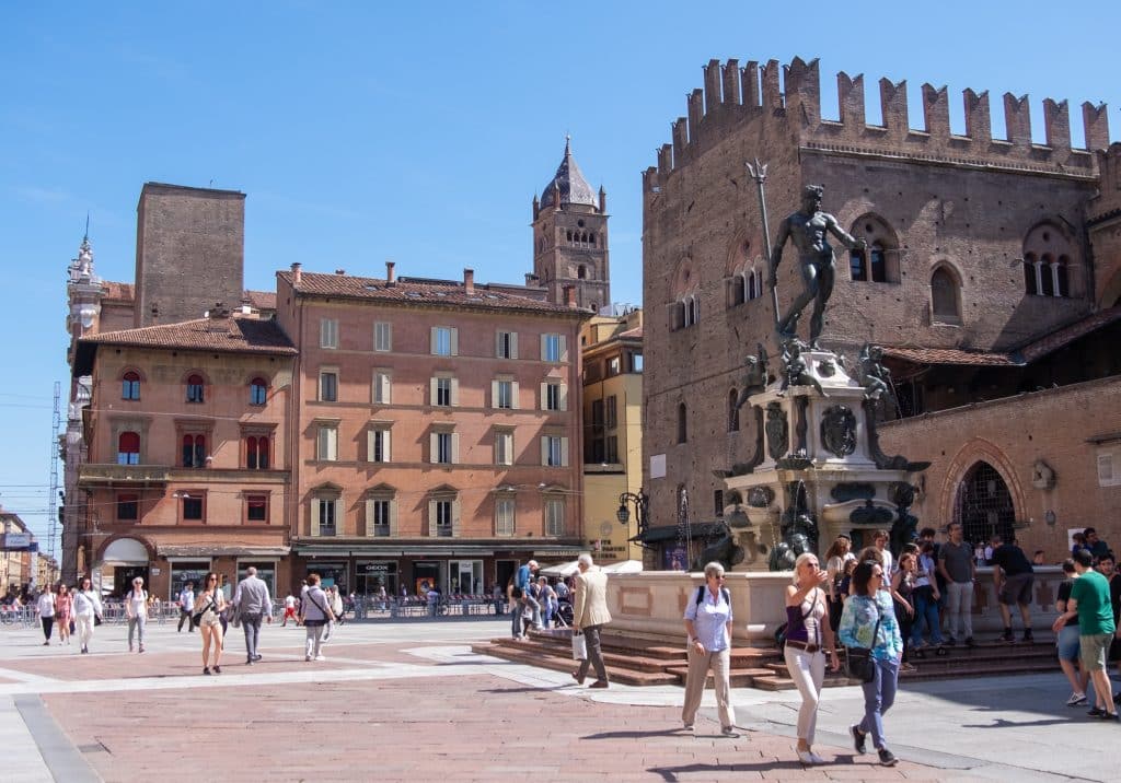 Bologna's Piazza Maggiore, a bit wide square with people walking by, and big fountain with a naked man on top (the god Neptune).