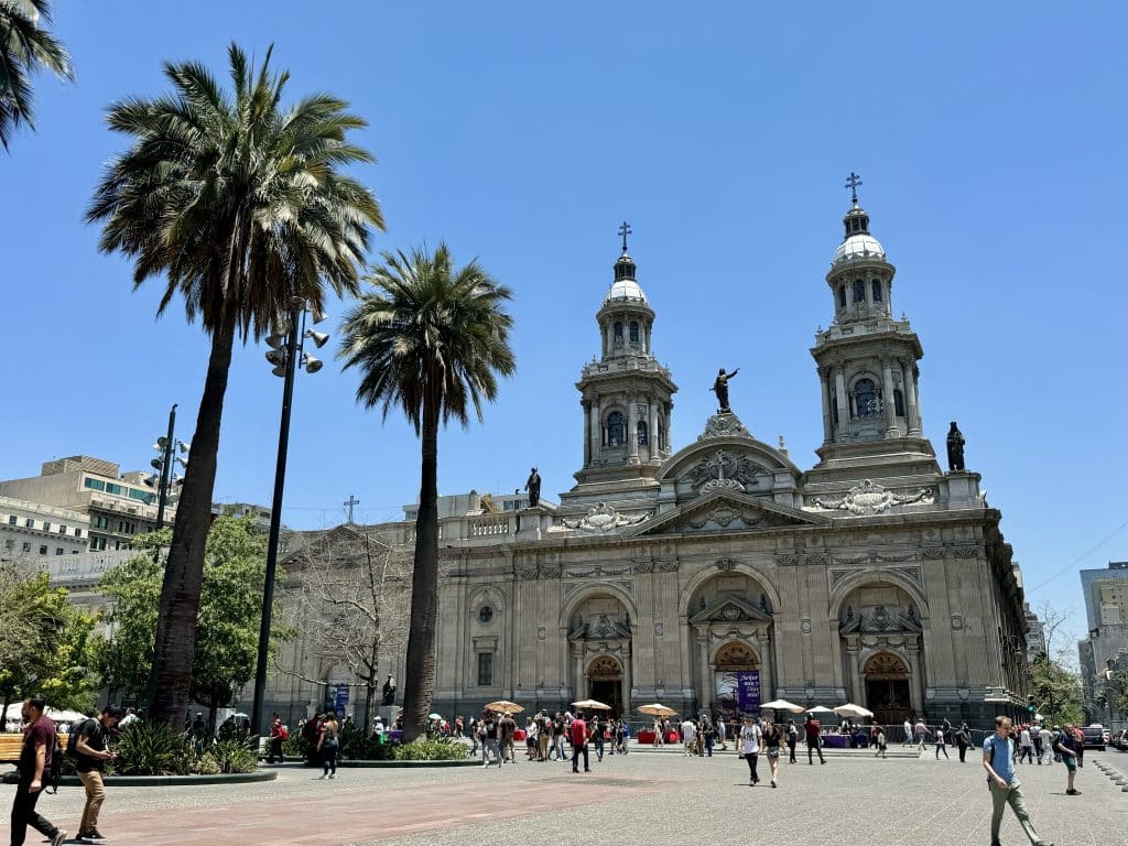 A big square in Santiago with tall palm trees and a church on one side.