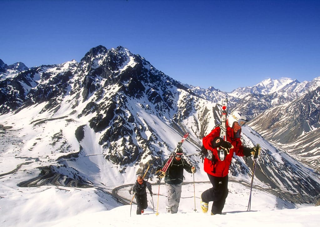 Three people climbing a snowy mountain in ski gear.