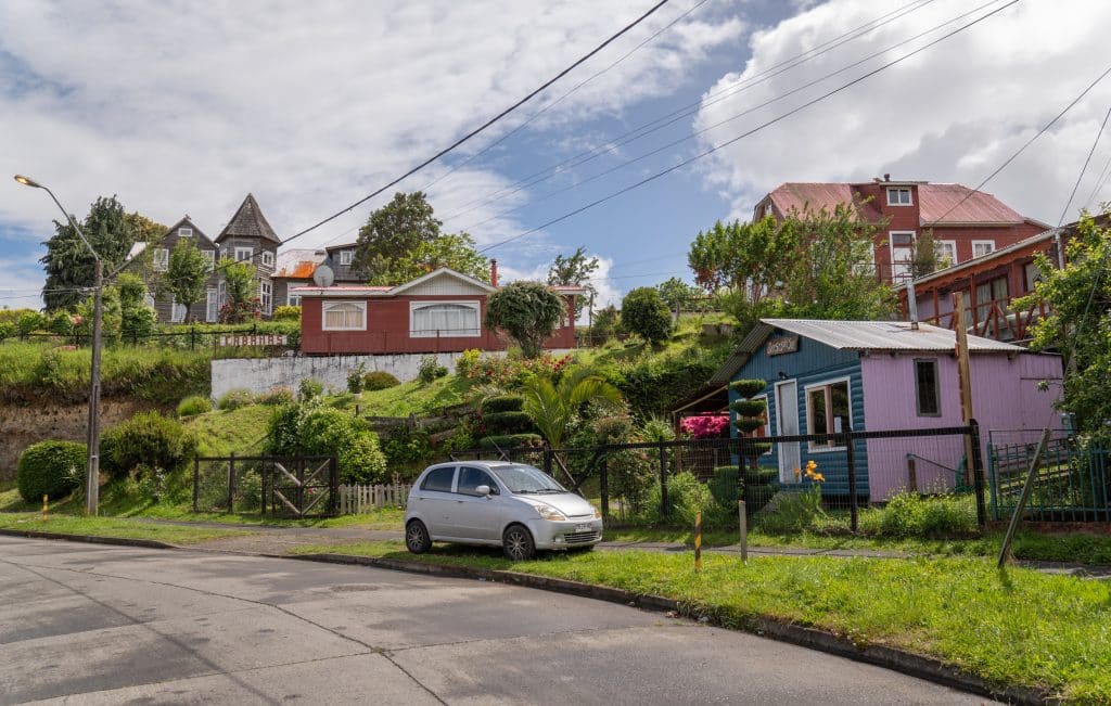 Brightly painted small houses in Puerto Octay, set on an overgrown hillside.
