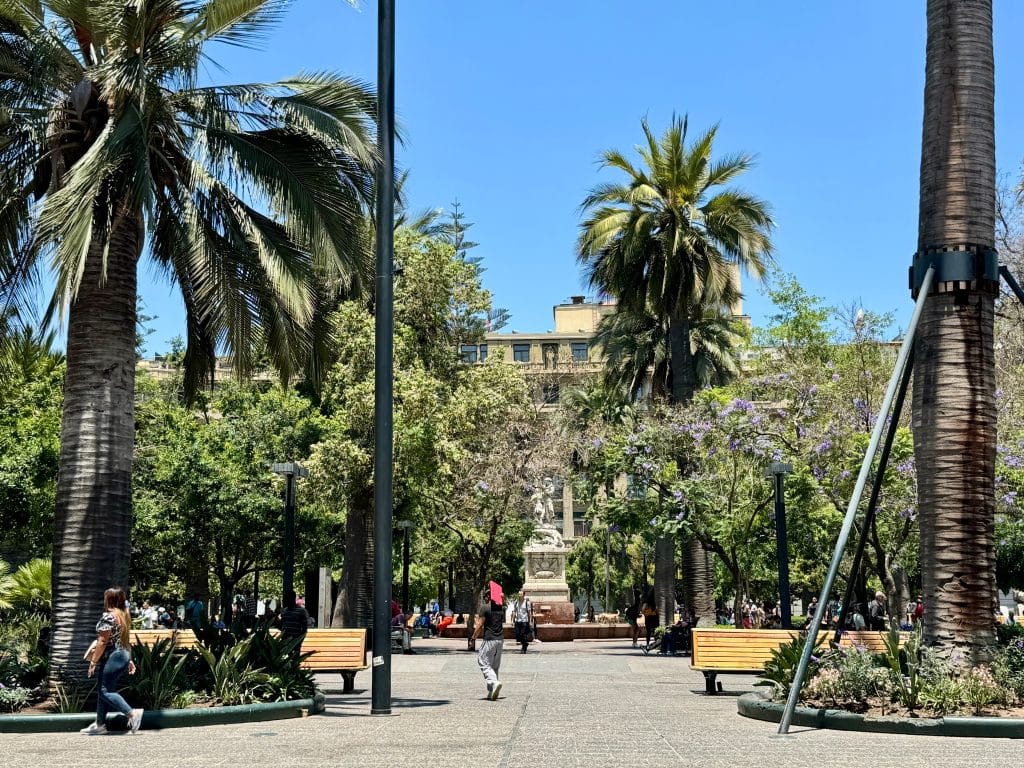A public park in Santiago, Chile, with palm trees, a fountain, and benches.