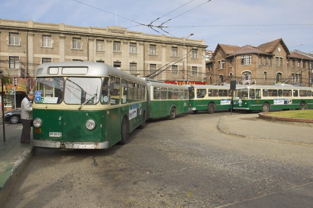 A line of old-fashioned green and cream-colored trolley buses that look like a VW bus from the front.