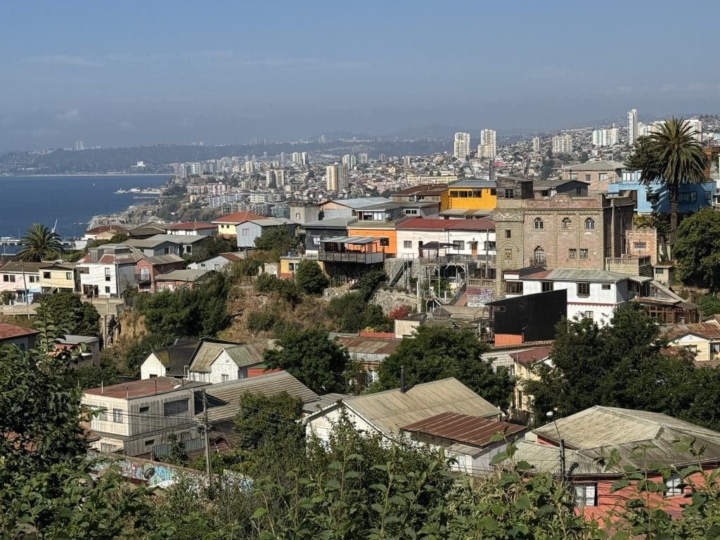 Views of Valparaiso from above, with colorful buildings atop several hills, pushed up against the coastline.