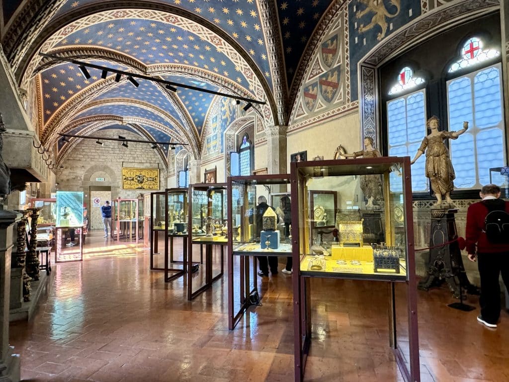 A museum with beautifully curved ceilings painted midnight blue with golden stars. There are glass and wood cabinets featuring small treasures.