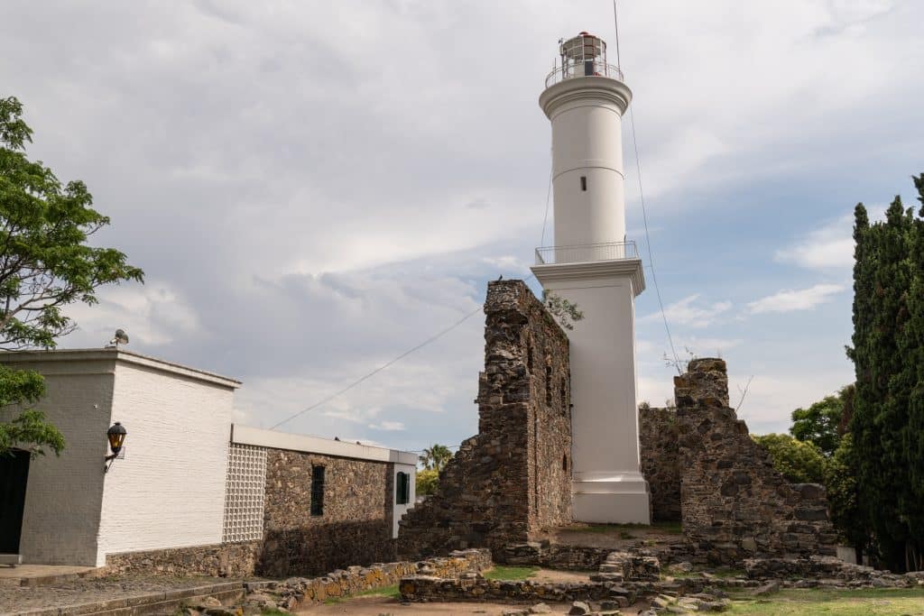 A tall, white, skinny lighthouse built into a rocky base.