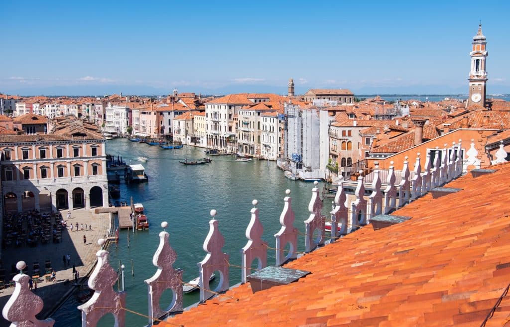 The view of the big Grand Canal in Venice from a rooftop deck, with an orange roof in the foreground.