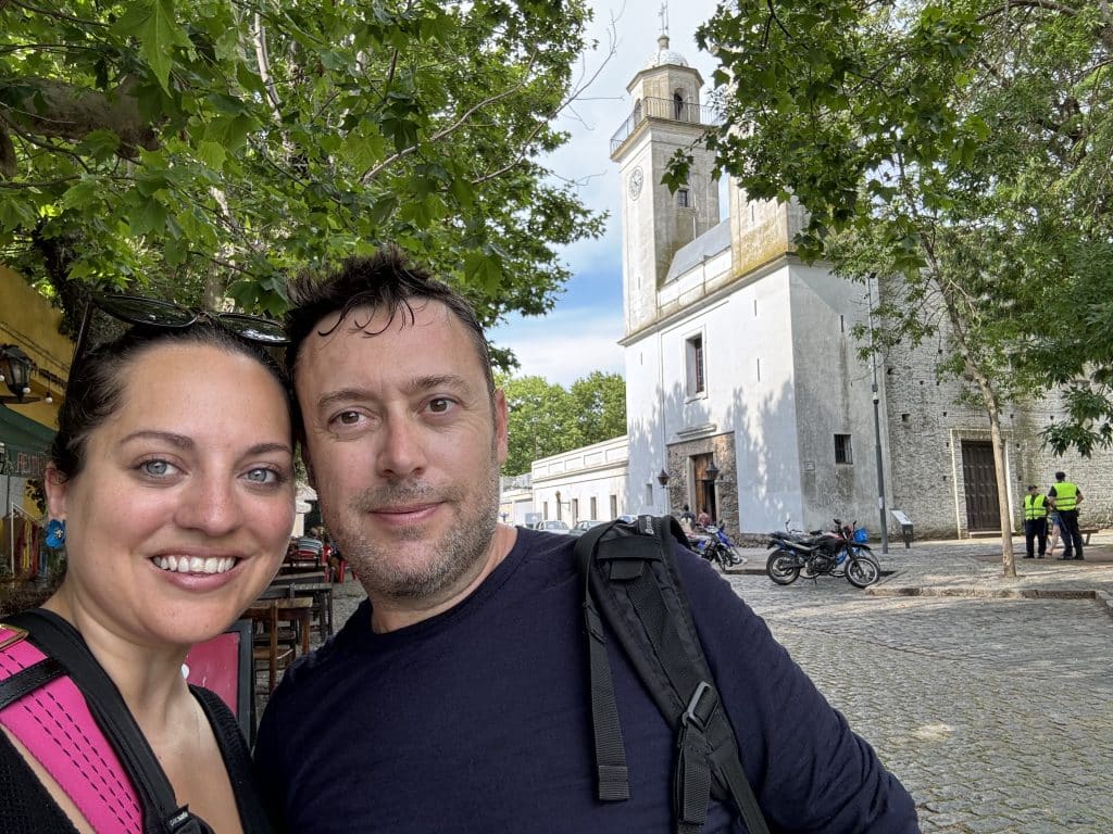 Kate and Charlie taking a sweaty smiling selfie in front of a big white church.