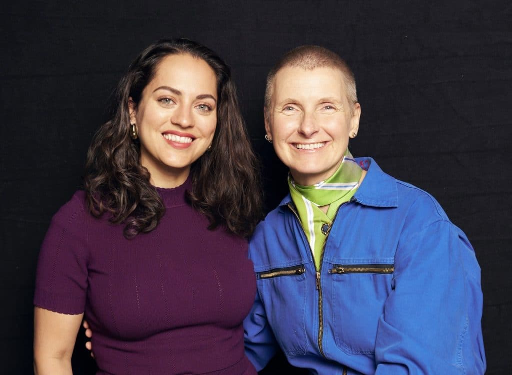 Kate and author Elizabeth Gilbert smiling in a Portrait together. Kate wears a royal purple top; Elizabeth wears a bright blue jumpsuit.