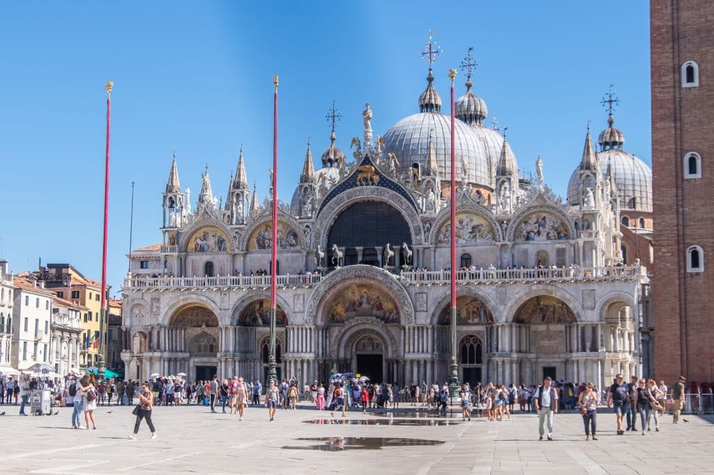 Basilica San Marco, a huge church with tons of domes topped with slender steeples, surrounded by tourists.
