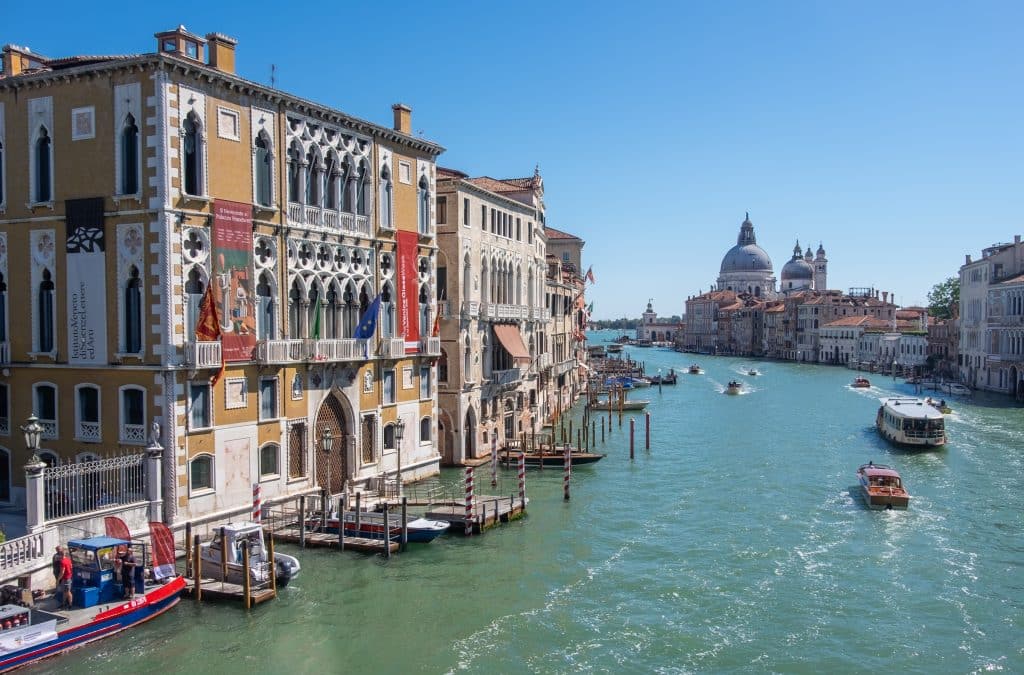 Venice's Grand Canal, lined with colorful buildings, and in the background, a church with a large dome.